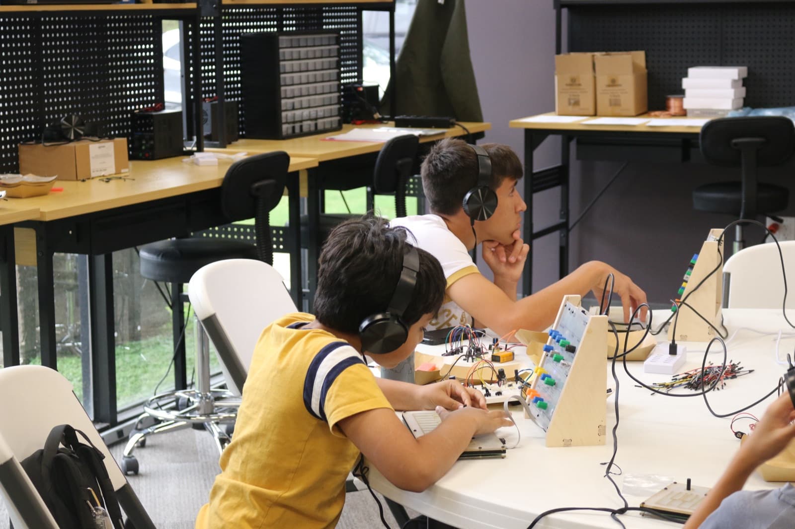 Campers with headphones on, playing the synthesizers they built