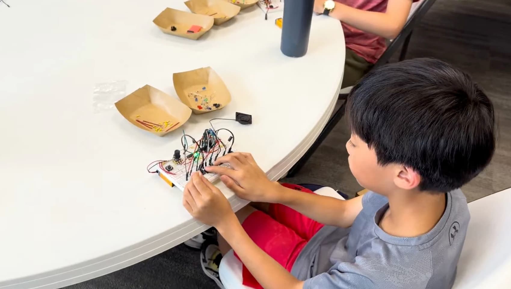 Close-up of a camper wiring up a breadboard audio circuit