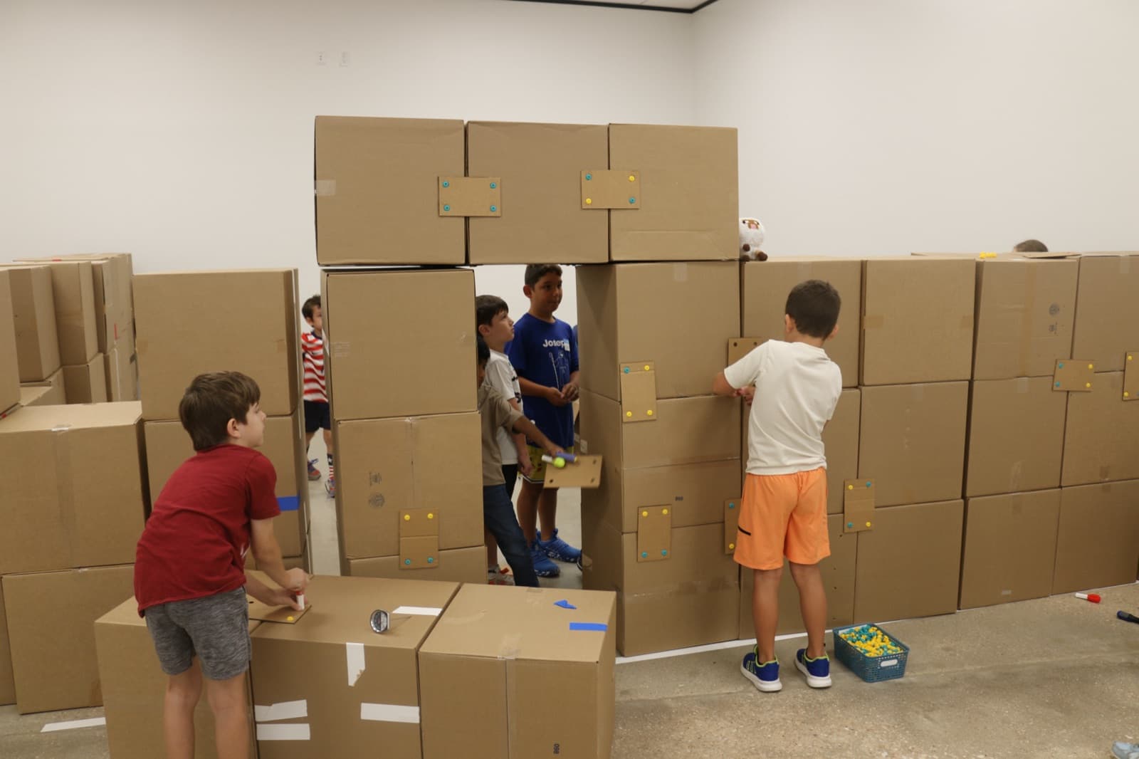 Campers building a walk-in fort out of full-size cardboard boxes