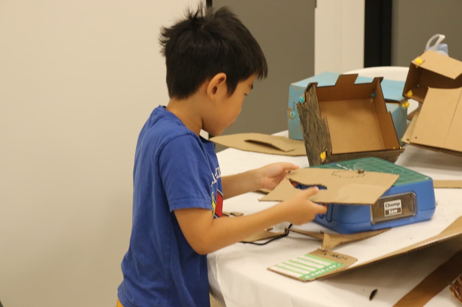 Young camper assembling a cardboard build at the work table
