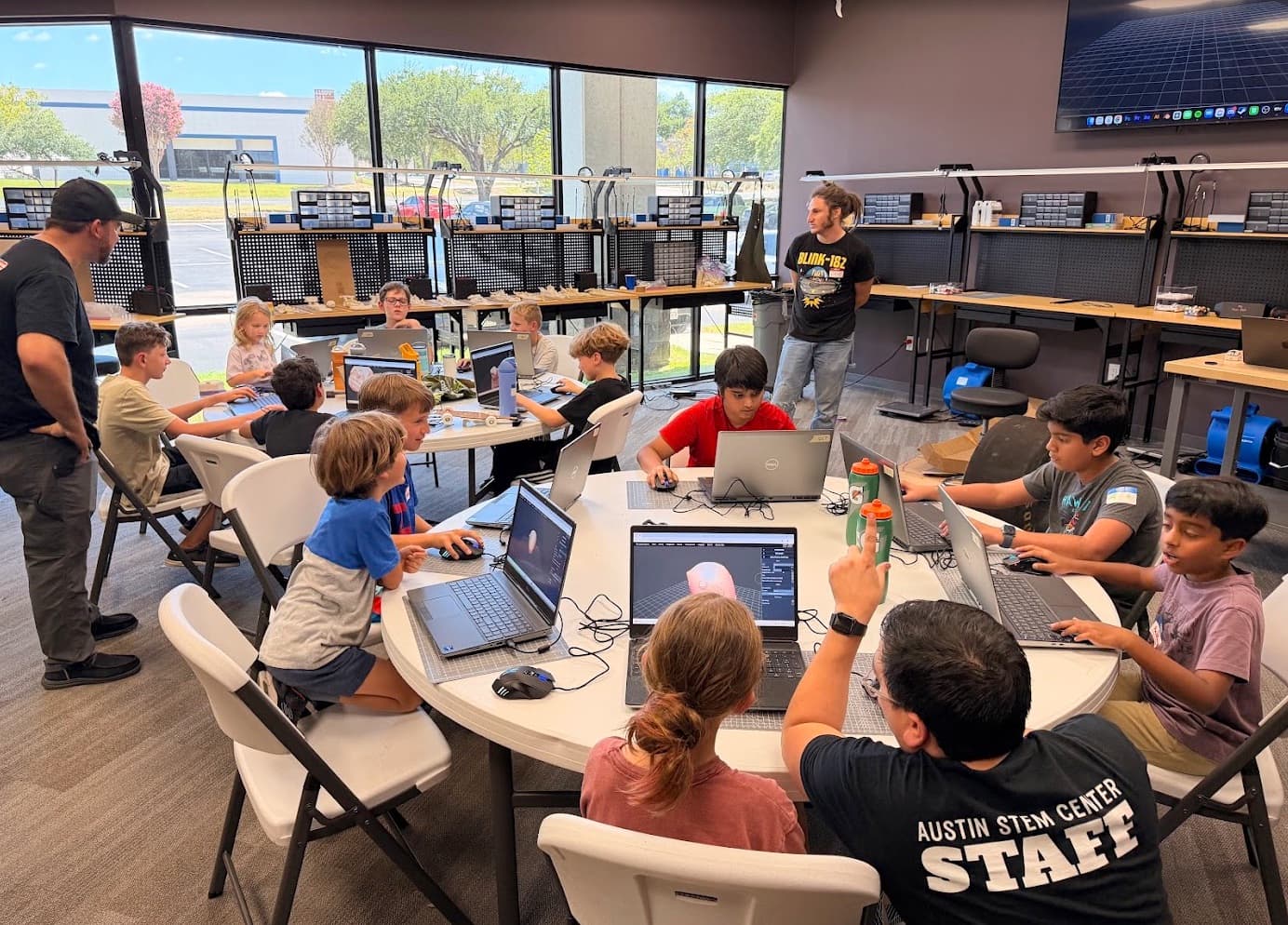Campers designing their cars on laptops around the lab table