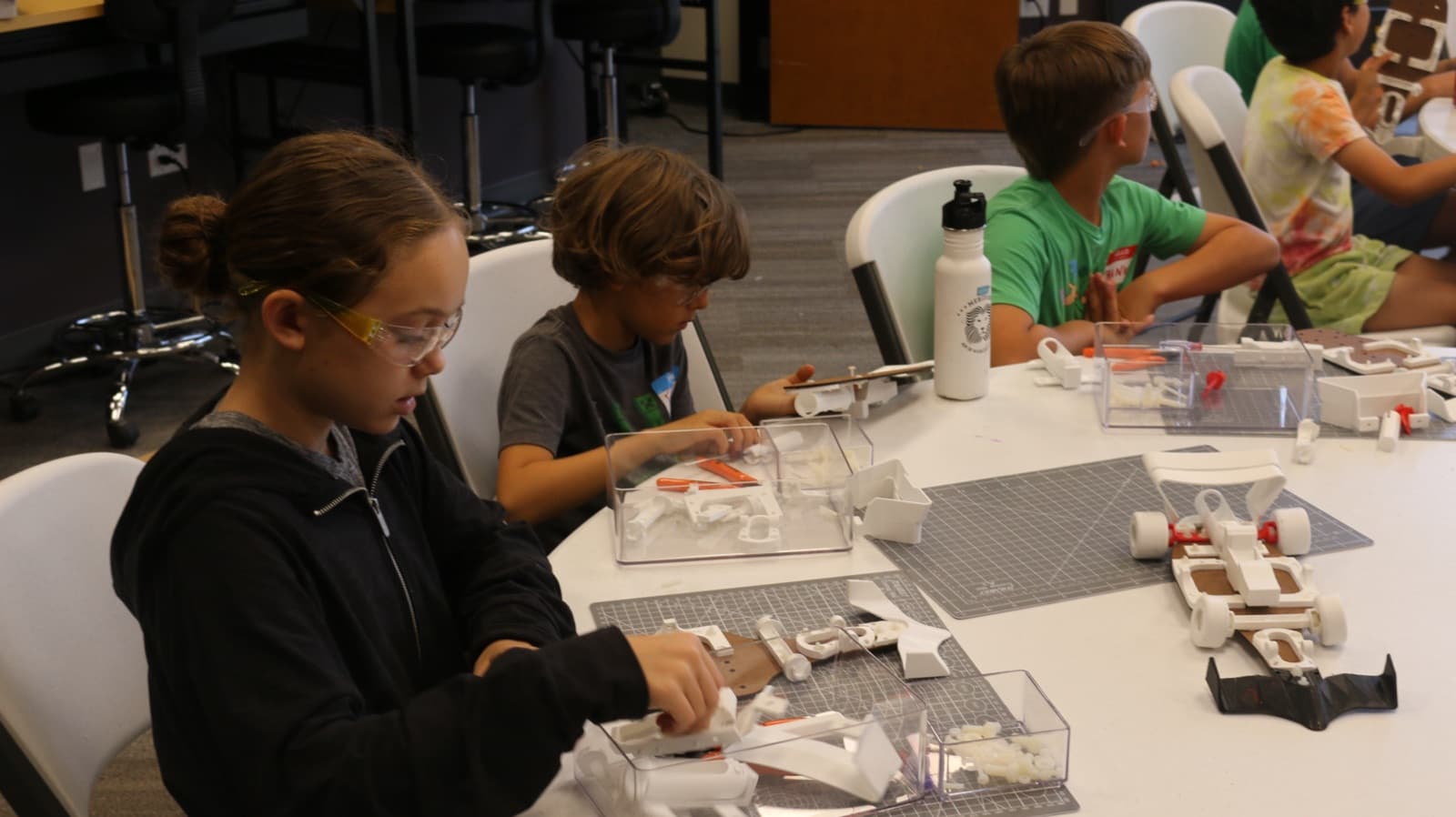 Campers in safety glasses assembling their race car kits